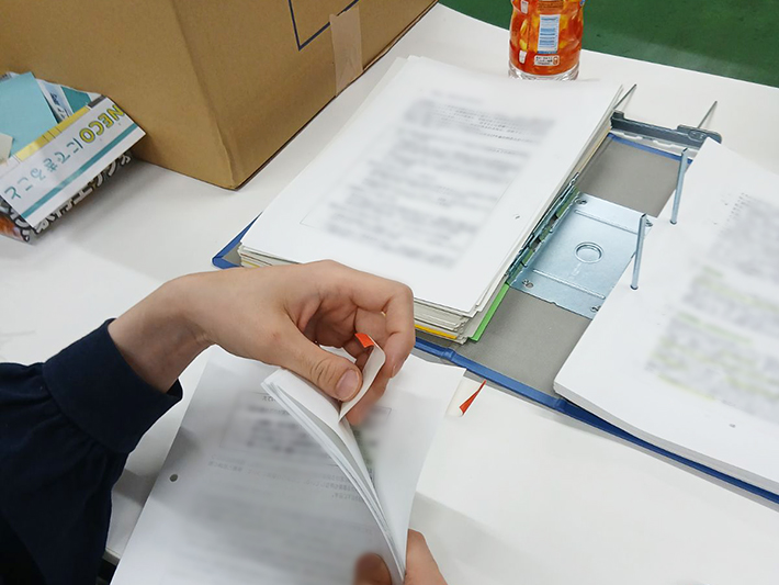 スキャンの妨げや機器の故障を防ぐため、資料についている付箋を一つひとつ丁寧に取り外している様子。