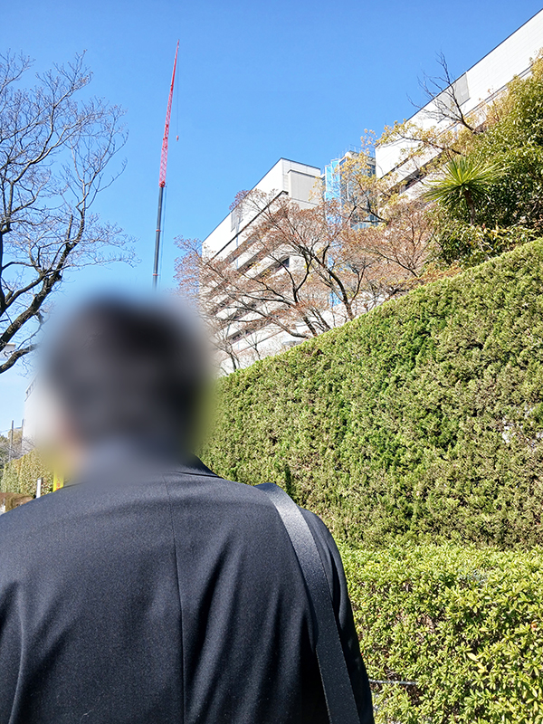名古屋市内の大学での実習面談会へ向かう訓練生。背景にそびえるビル群を背に、求人票だけでは分からない『職場の空気感』を肌で感じるための大切な一歩