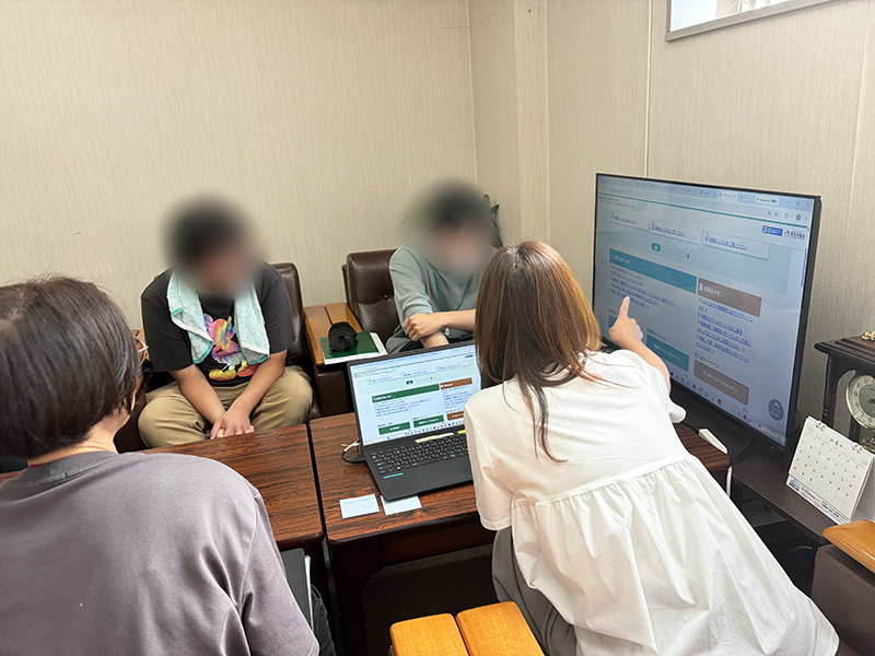 求人検索サイトの入力画面を指差し、職種や希望勤務地といった詳細な条件をどのように設定するか、一人ひとりのペースに合わせて一つひとつ丁寧に操作説明を行う就労支援員の安井。