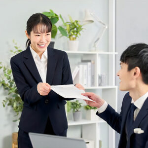職場におけるマナーの本質である「相手への配慮」を体現する労働者のイメージ図。うなずきによる適切なリアクションや、周囲の集中を妨げない声の大きさなど、マニュアルにはない「暗黙のルール」を意識して、お互いが気持ちよく働ける環境を築いている様子。