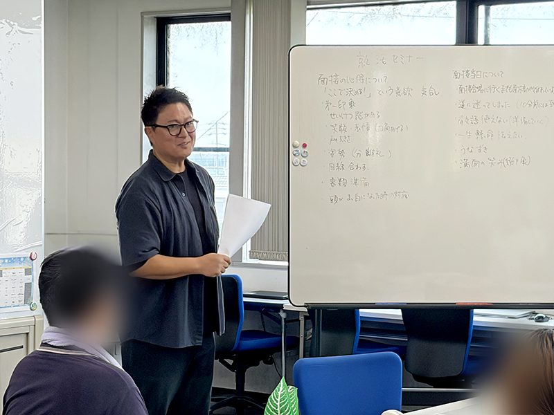 面接の心得や配慮事項の伝え方をホワイトボードに箇条書きでまとめ、訓練生へ向けて詳しく解説する渡邉理事長。「綺麗な回答よりも誠実な姿勢」が大切であるという、障害者雇用の現場に即したアドバイスを送る講義シーン。
