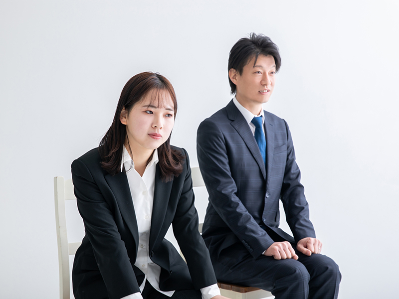 面接会場の待機室において、背筋を伸ばして椅子に並んで座る男女のイメージ。セミナーで学んだ「第一印象の重要性」や「早めの現地到着による心の準備」を実践し、自分らしさを発揮しようと備える静かな決意の瞬間。