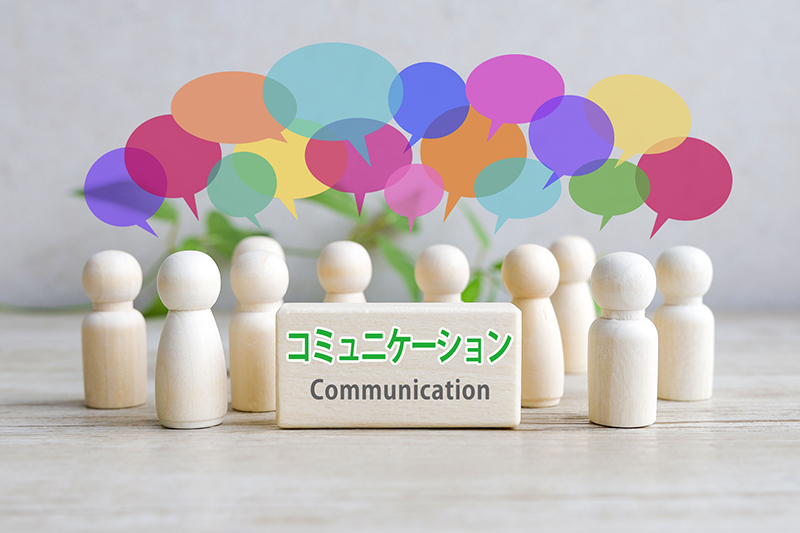 「TEAM」というカラフルなアルファベットブロックの周りにミニチュアの人型フィギュアが配置されたイメージ画像。一人ではなくチームで目標を共有し、互いに支え合いながら働く連携・チームワークを表現。